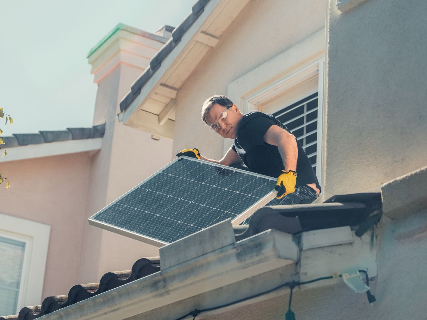 Monteur trägt Solarmodul auf ein Dach